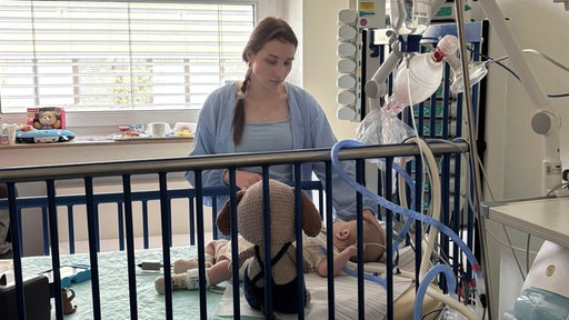 Der kleine Marcel liegt in einem Bett auf der Kinderintensivstation der Uniklinik Essen mit Mutter Maryna, die daneben steht und ihm den Kopf streichelt