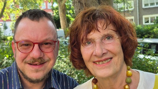 Zwei Menschen gucken in die Kamera: auf der linken Seite Tim Puffler und rechts seine Adoptivmutter Monika Reidegeld. 