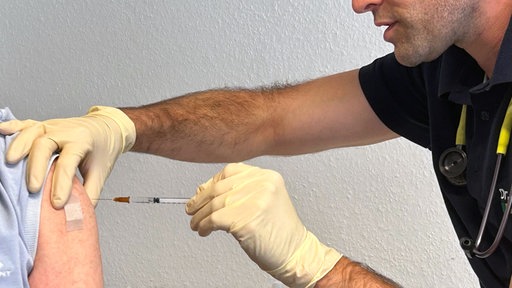 Der Arzt impft eine Patientin.