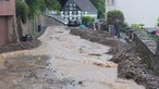 Durch eine Straße läuft braunes Wasser, rechts und und linkd davon liegt Gestein