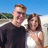 Ein junges Paar steht vor einem Flugzeug