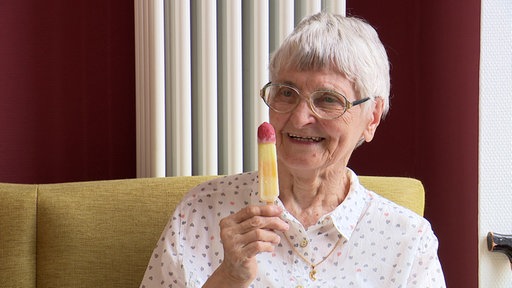 Lächelnde alte Dame mit einem Wassereis in der Hand