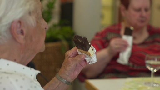 Senioren sitzen an einem Tisch und essen Eis