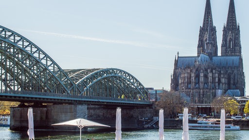 Der Kölner Dom mit mit einer Brücke und dem Rhein im Vordergrund. 