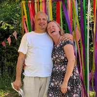 Ein Mann und eine Frau, ein Hochzeitspärchen in Rösrath, umarmen sich - dahinter sind bunte Girlanden