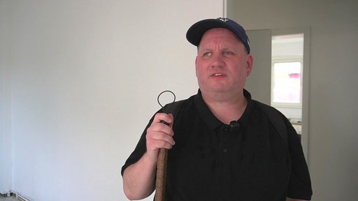 Ein Mann steht in einer frisch renovierten Wohnung, er ist im Portrait zu sehen
