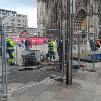 Auf der Kölner Domplatte parkt ein Baustellenfahrzeug und Bereiche sind mit Gitterzäunen für Bauarbeiten abgesperrt.