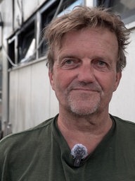 Achim Pesch, Eigentümer Sürther Bootshaus, steht auf dem Steg vor dem abgebrannten Boot.