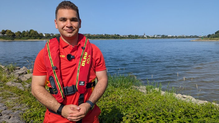 Kian Shahbodhaghi vom DLRG steht am Rhein in Köln-Rodenkirchen.