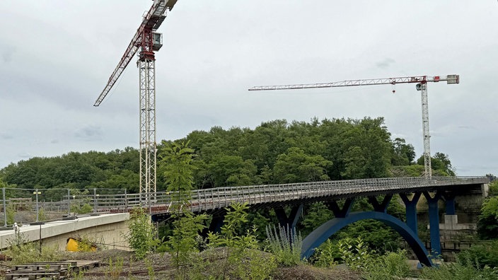Kräne stehen neben der gesperrten Autobahnbrücke der A4.