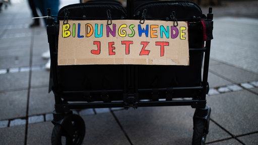 Demo-Schild mit der Aufschrift "Bildungswende jetzt" hängt an einem Bollerwagen