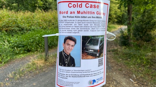 Ein Fahndungsplakat zum Tod von Muhittin Güney hängt in einem Kölner Waldstück.
