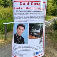 Ein Fahndungsplakat zum Tod von Muhittin Güney hängt in einem Kölner Waldstück.