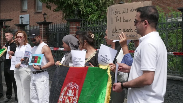 Menschen mit einer afghansichen Flagge stehen nebeneinander