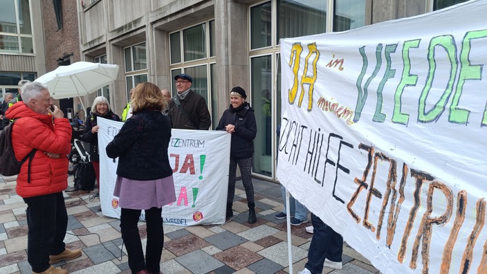 Demonstrierende Menschen stehen vor dem Rathaus in Köln.