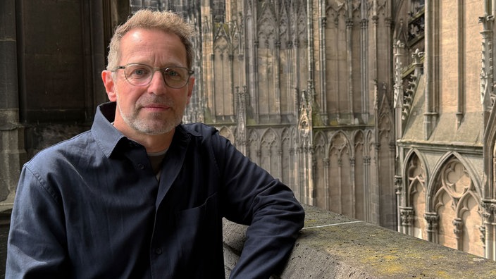 Dombaumeister Peter Füssenich schaut vor der Fassade des Kölner Doms in die Kamera.