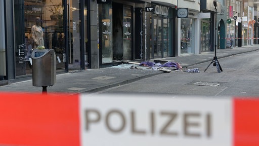 Scherben und Kleidungstücke liegen vor einem Geschäft in der Ehrenstraße in Köln