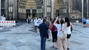 Dutzende Menschen stehen auf der Domplatte vor dem Hauptportal des Doms Schlange