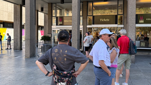 Mehrere Personen stehen auch beim Ticketverkauf neben dem Dom Schlange