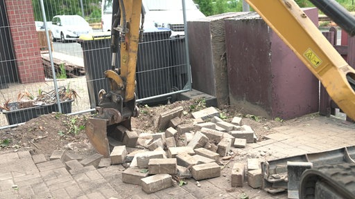 Bagger reißt Steine auf
