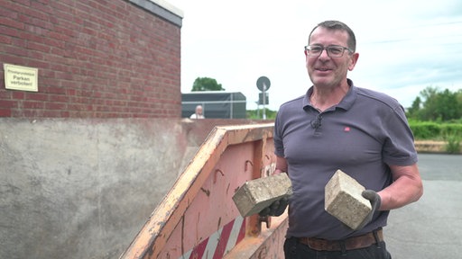 Frank Hunze mit Steinen in der Hand vorm Container