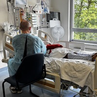 Mann sitzt an einem Krankenhausbett