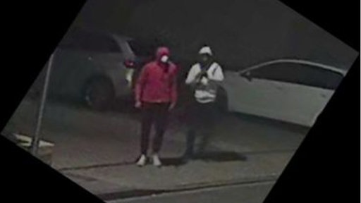 2 Männer in Kapuzenpullovern stehen nachts auf einem Parkplatz