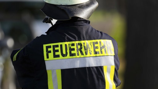 Feuerwehrmann von hinten, auf dem Rücken Aufschrift "Feuerwehr"