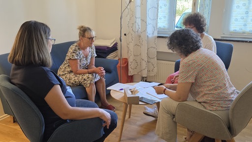 Vier Frauen sitzen in einem Stuhlkreis zusammen