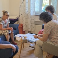 Vier Frauen sitzen in einem Stuhlkreis zusammen
