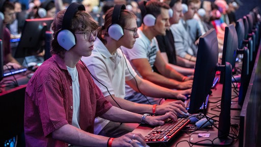 Mehrere Menschen sitzen mit aufgesetzten Kopfhörern vor Computerbildschirmen.
