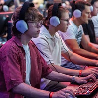 Mehrere Menschen sitzen mit aufgesetzten Kopfhörern vor Computerbildschirmen.