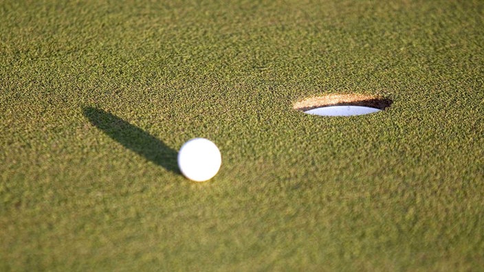 Golfball rollt auf das Loch zu