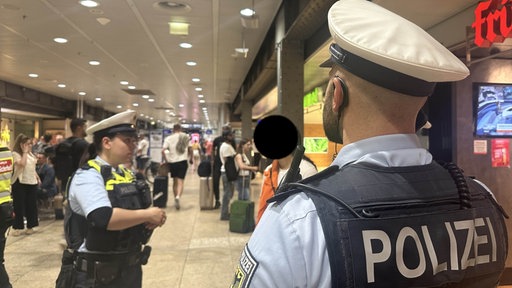 Zwei Polizisten kontrollieren eine Frau im Kölner Hauptbahnhof.