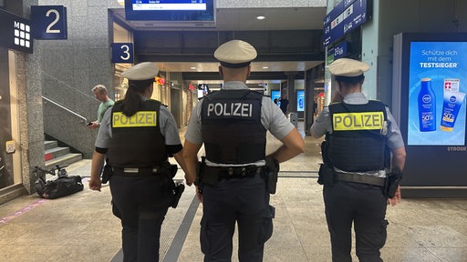 Drei Polizeieinsatzkräfte von hinten. 