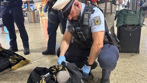 Ein Polizist kontrolliert eine schwarze Tasche.