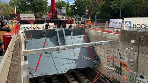 Das Hochwasserschutztor wird an den Bahngleisen platziert.