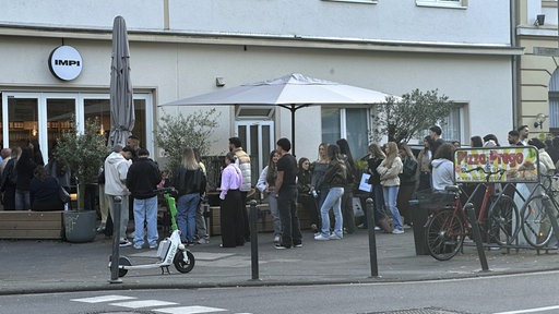 Eine lange Schlange junger Menschen vor dem Impi-Café in Köln-Ehrenfeld