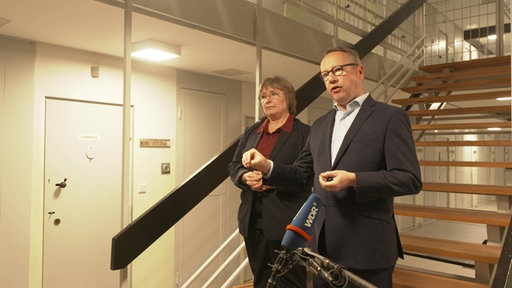 Angela Wotzlaw, Leiterin der JVA Köln, und Benjamin Limbach, NRW-Justizminister, stehen zusammen auf einer Treppe in der JVA Köln