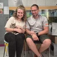Kätzchen Olivia sitzt auf dem Schoß einer Frau, daneben sitzt ein Mann.