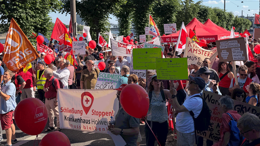 Auf dem Bild erkennt man eine Gruppe an Protestierenden. Sie halten Schilder hoch