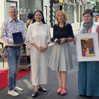 vier Personen stehen auf der Ehrenstrasse in Köln und halten verschiedene Kunstwerke hoch