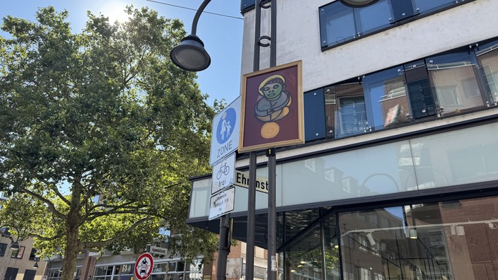Ein Gemälde hängt an einer Laterne in der Ehrenstrasse in Köln