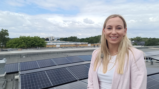 Sira Müller von der Genossenschaft "Die Ehrenfelder" steht auf dem Flachdach mit der neuen Photovoltaikanlage.