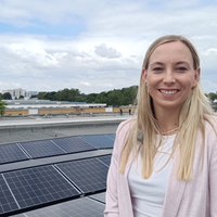 Sira Müller von der Genossenschaft "Die Ehrenfelder" steht auf dem Flachdach mit der neuen Photovoltaikanlage.