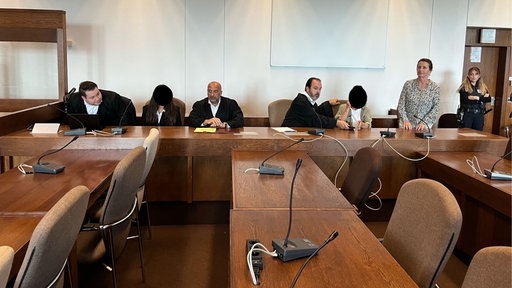 Anwälte, Angeklagte und Übersetzerin im Gerichtssaal