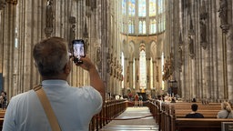 Ein Besucher des Kölner Doms fotografiert mit dem Handy.
