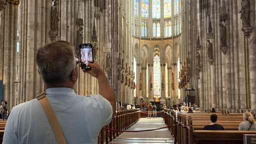 Ein Besucher des Kölner Doms fotografiert mit dem Handy.