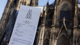 Eine Touristin zeigt ihr Ticket vor dem Kölner Dom.
