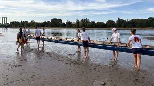 Ruderer setzen ihr Boot in den Rhein.